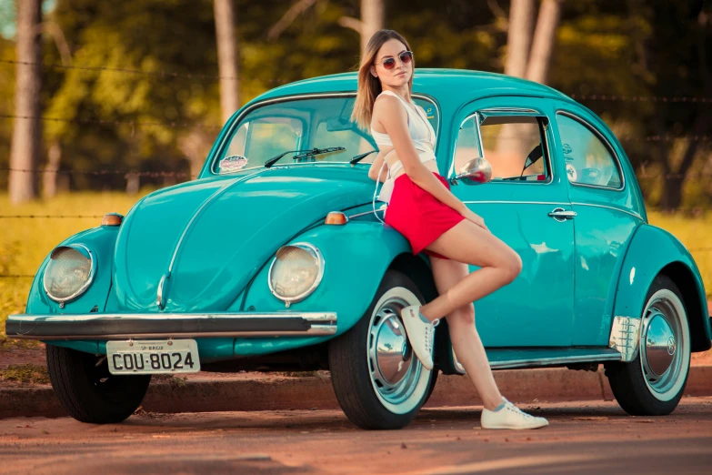 a girl leaning on a vw beetle in the street