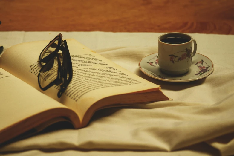 an open book with sunglasses sits on the table