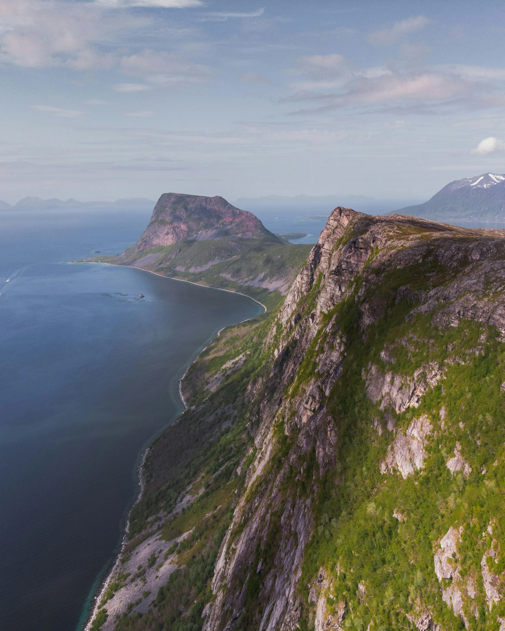 a rocky cliff next to the ocean with mountains and sea