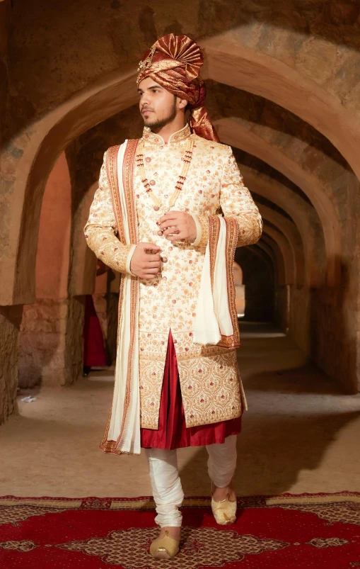 an indian groom in a wedding outfit posing for a pograph