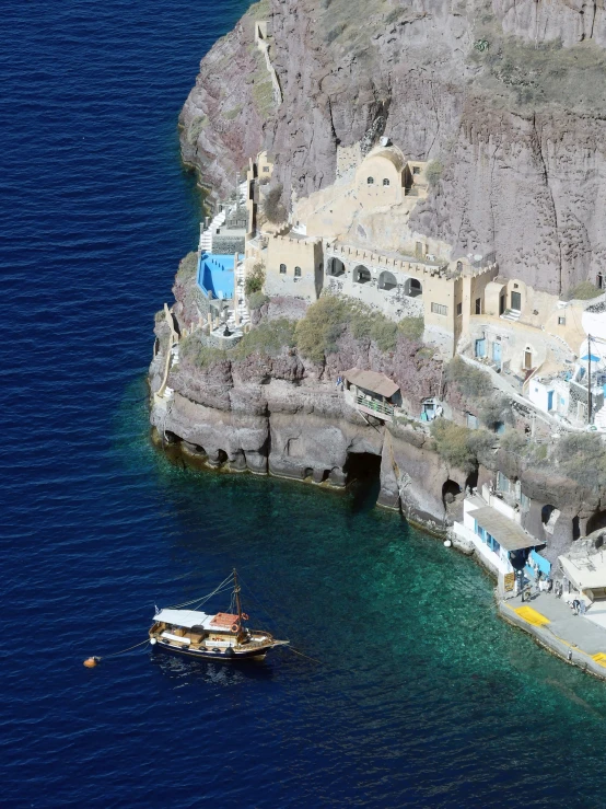 a boat on the water near a rocky cliff