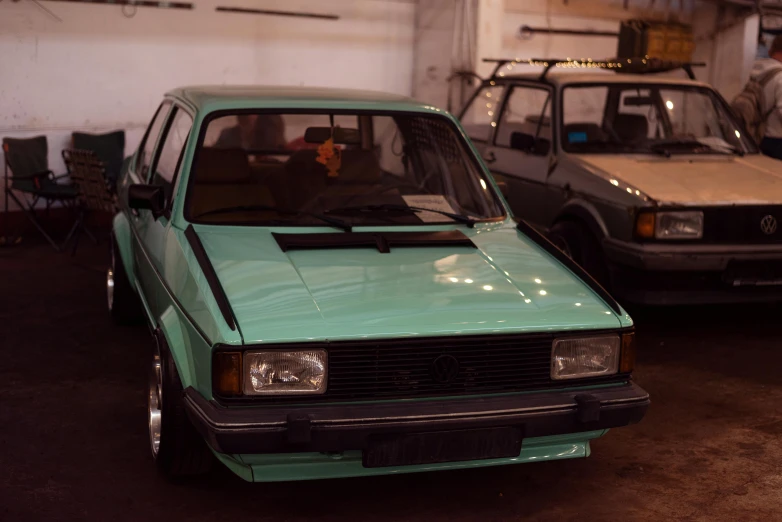 two vehicles parked in a garage next to a man standing