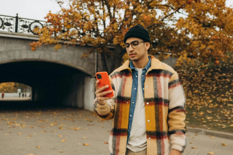 a man holding a cell phone while wearing a plaid jacket