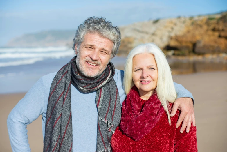 an older couple with white hair standing in front of a body of water