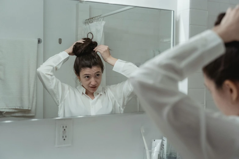 a woman is getting her hair in the mirror