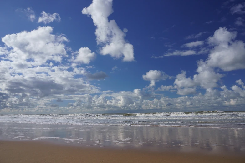 the sky is partly over a beach on the water