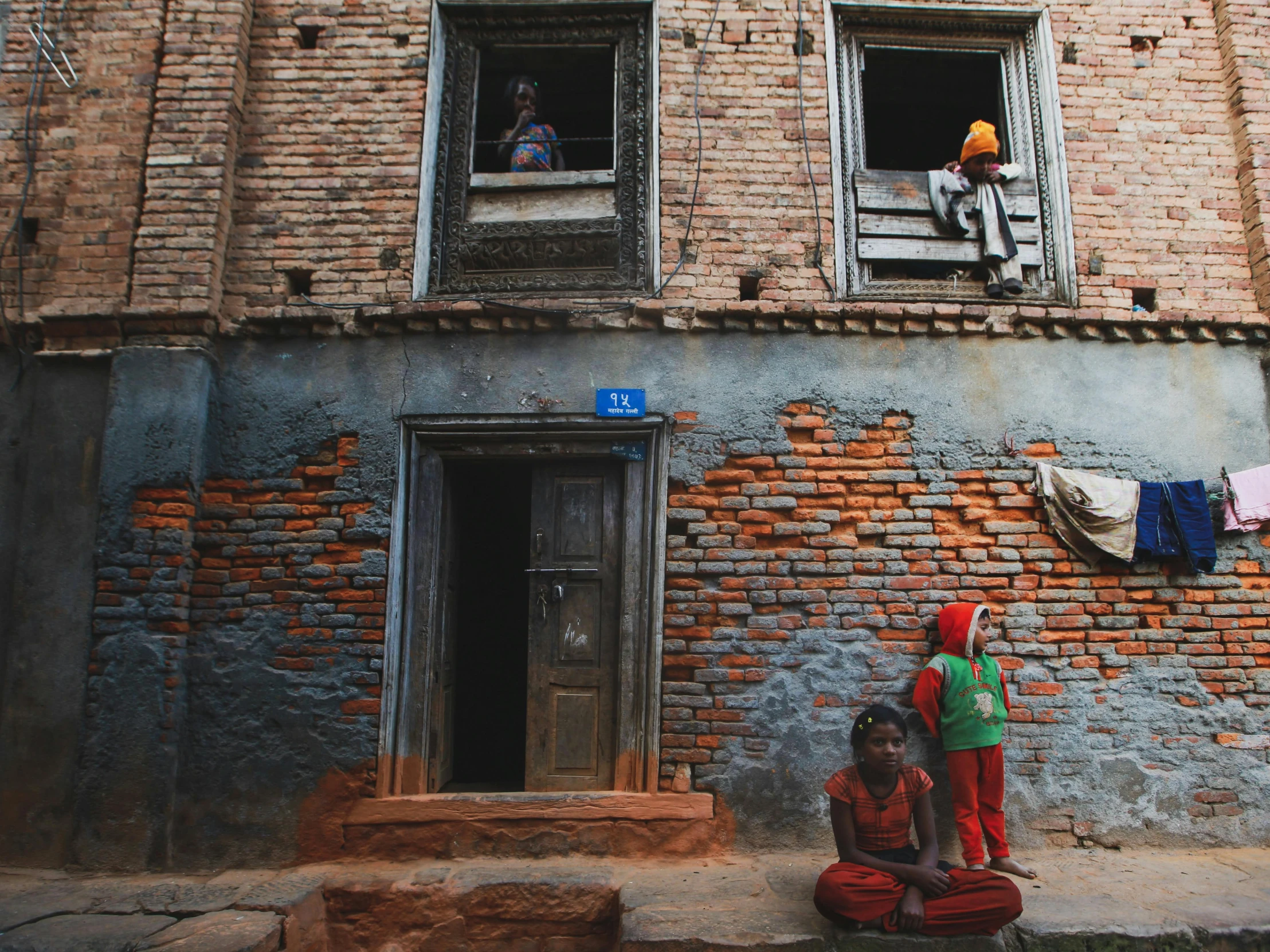 two s sit outside a building on their knees