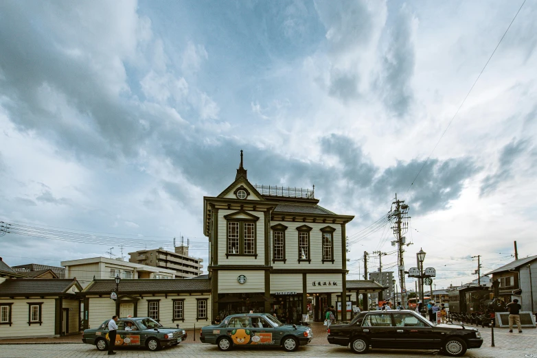 a town square with three old cars parked outside