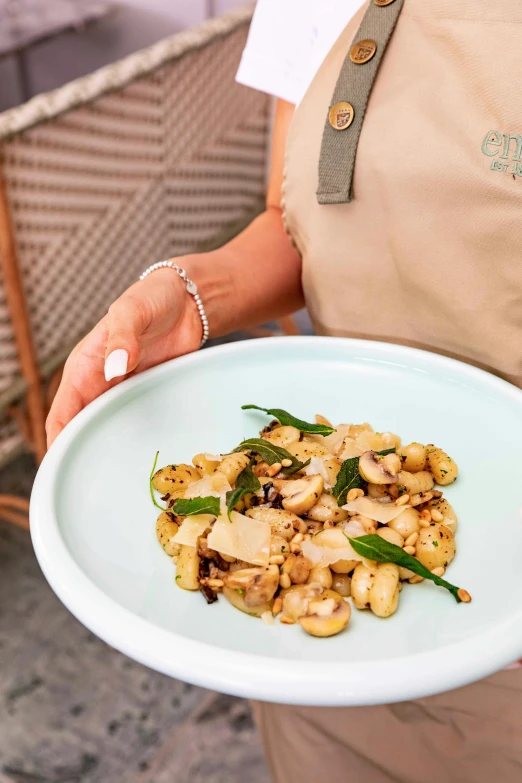 a person holds a plate of food made with mushrooms and sage