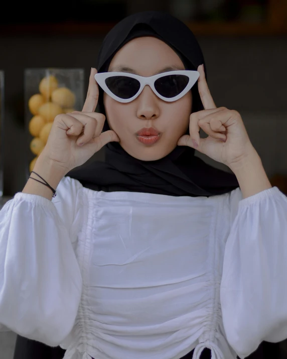 a woman in a dress holding sunglasses on her face