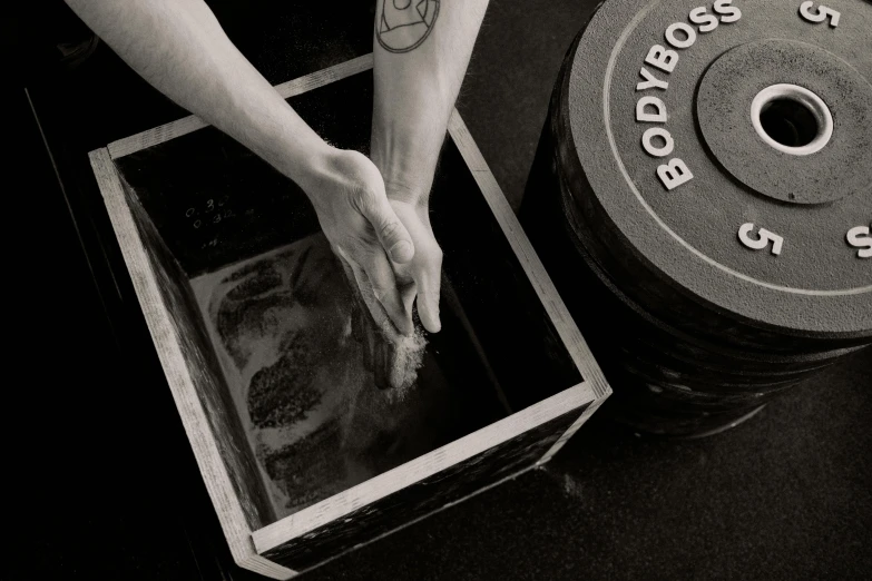 a person standing over an open box next to a barbell weight