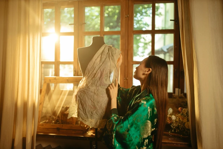 a woman in an oriental kimono looking at a mannequin dress on a mannequin
