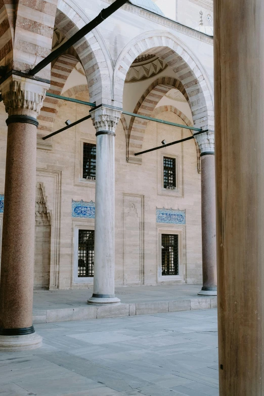 an empty and open courtyard with pillars, arches and windows