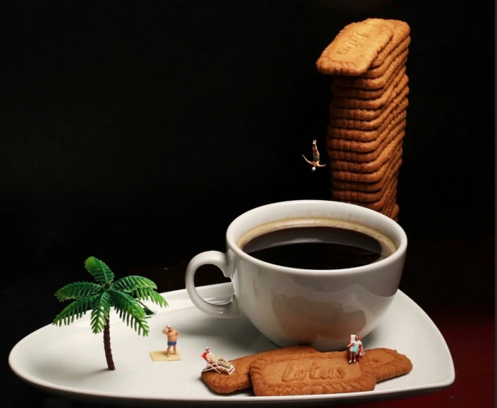 a white coffee cup is next to some cookies and a tree