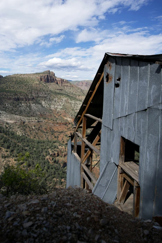 a rustic building on top of a mountain overlooking a cliff