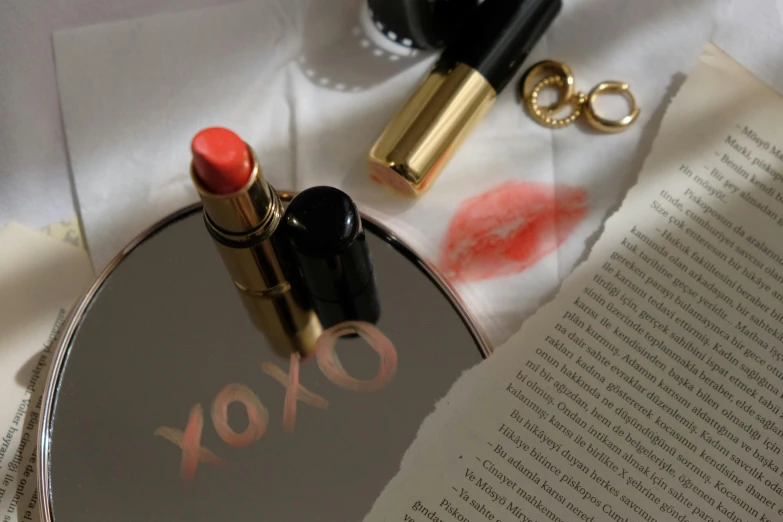 lipstick and golden accessories on the table beside an open book