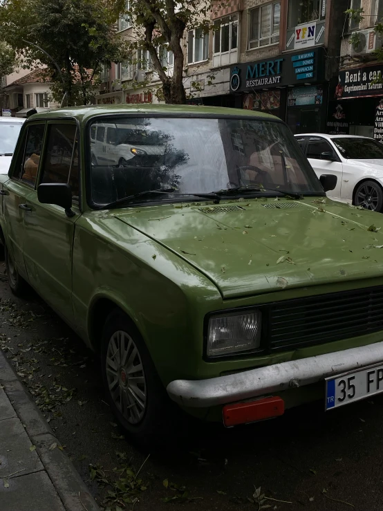 there is a small green car parked on the sidewalk