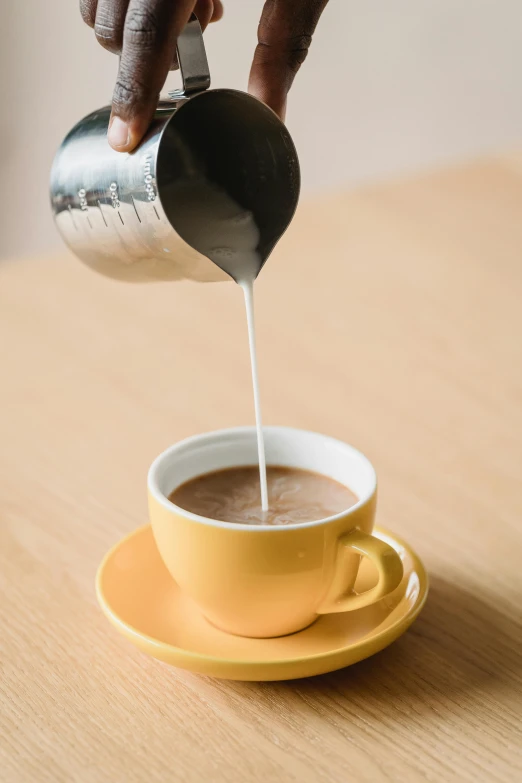 someone pours milk into a cup of coffee