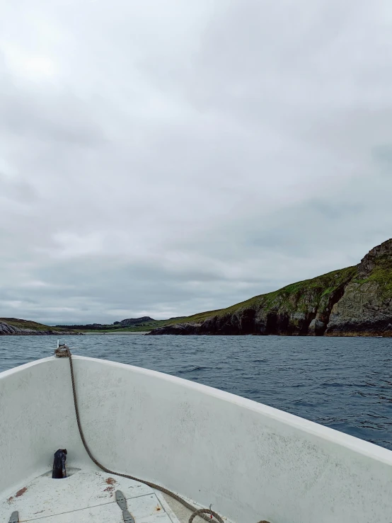 a boat is traveling in the water with hills on either side