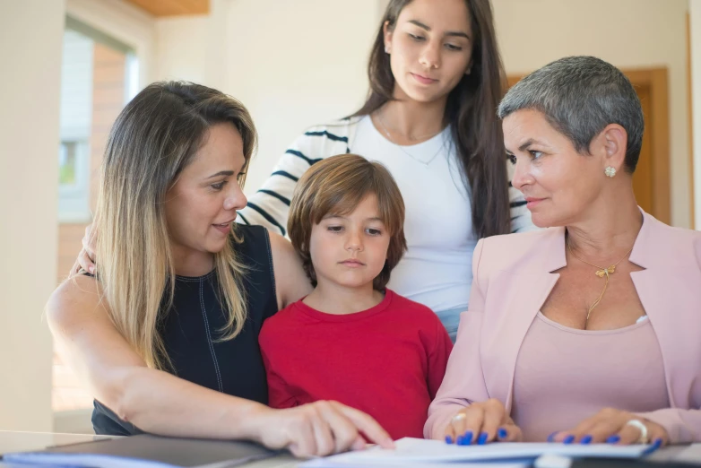 two ladies and a young child look at papers as they sit in a living room