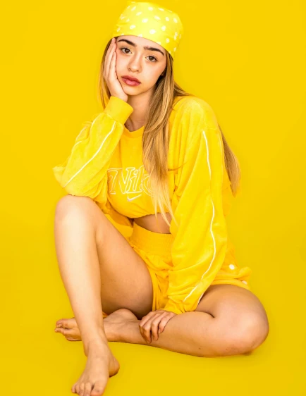 a girl sitting in a yellow outfit posing for the camera