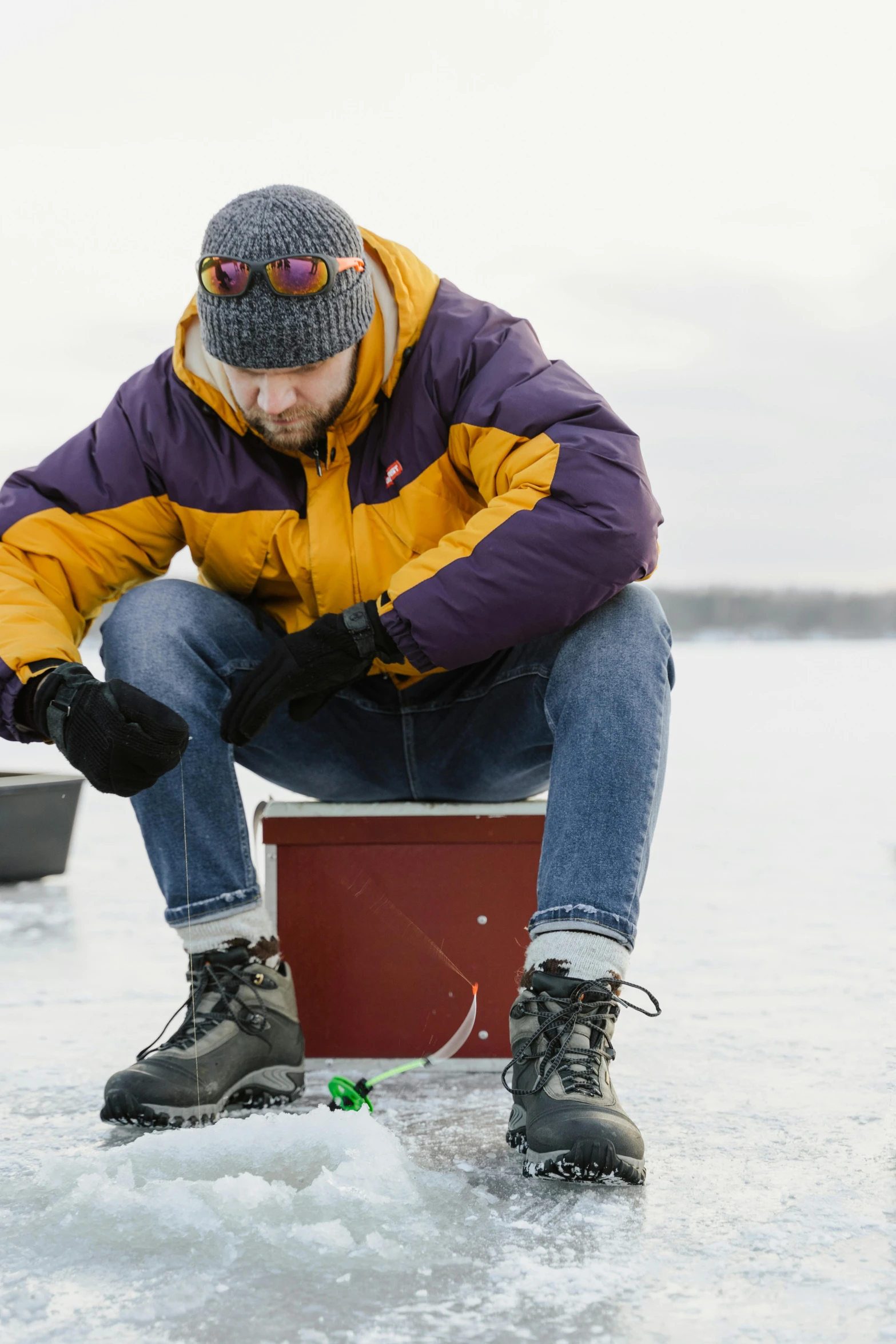 man crouching on a red box in frozen water