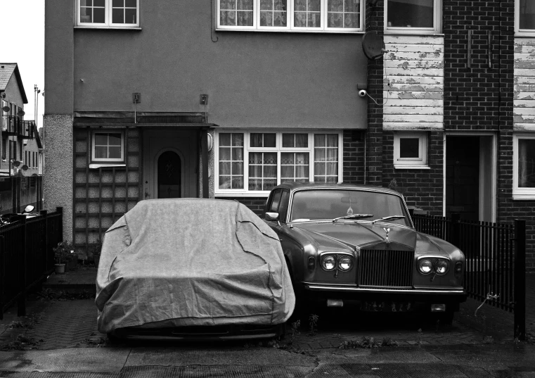 a car covered with a blanket parked next to a building