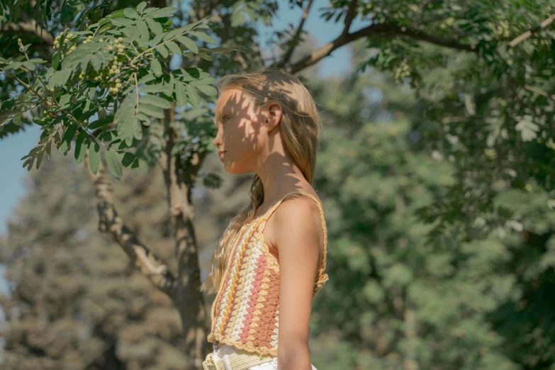 the little girl is standing by a tree looking over her shoulder