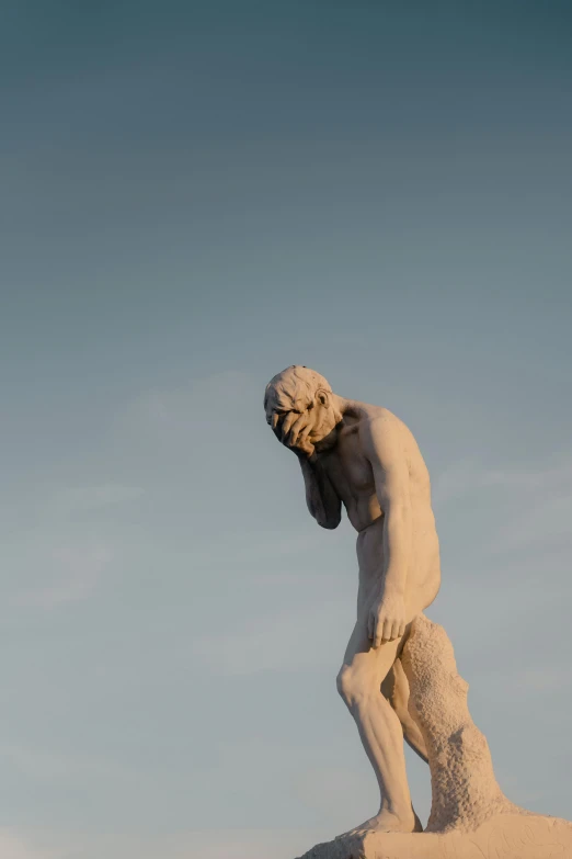 statue is standing upright on a hillside against a clear sky