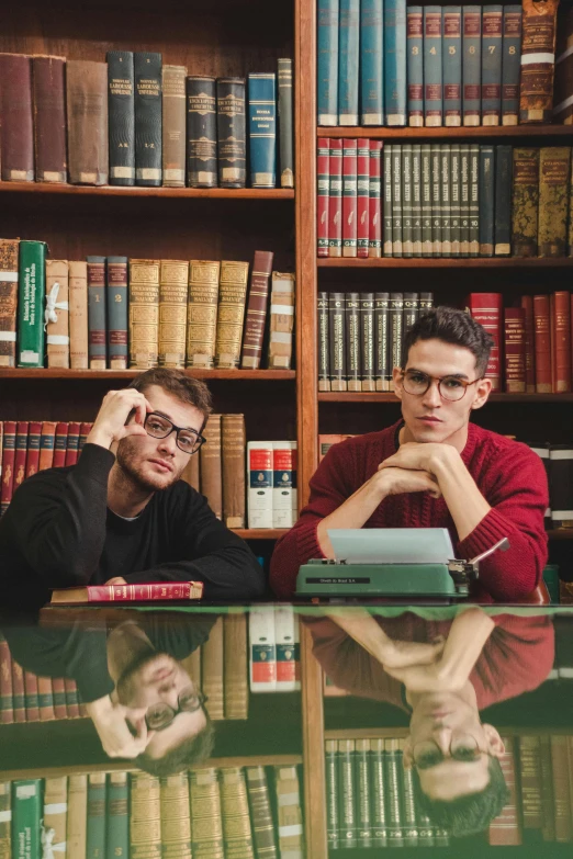 two young men sitting at a desk with their computers