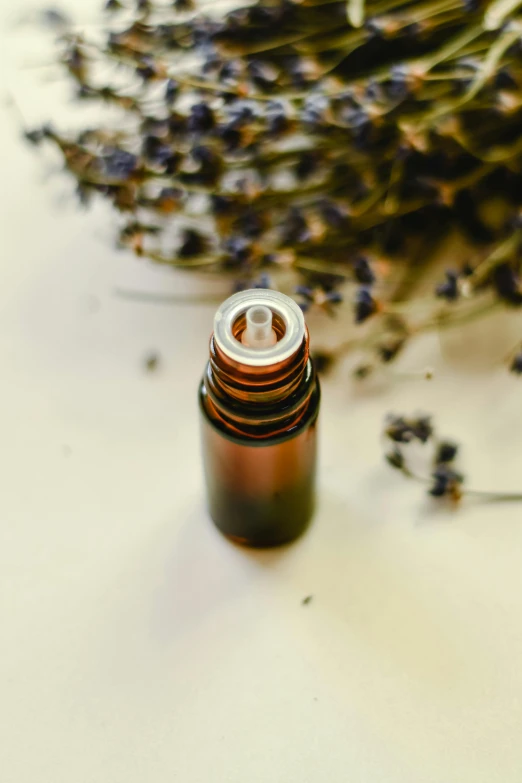 a small bottle of essential oils beside some flowers