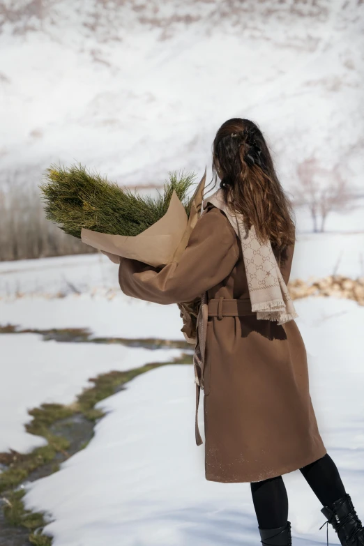 woman standing in snowy area holding some flowers