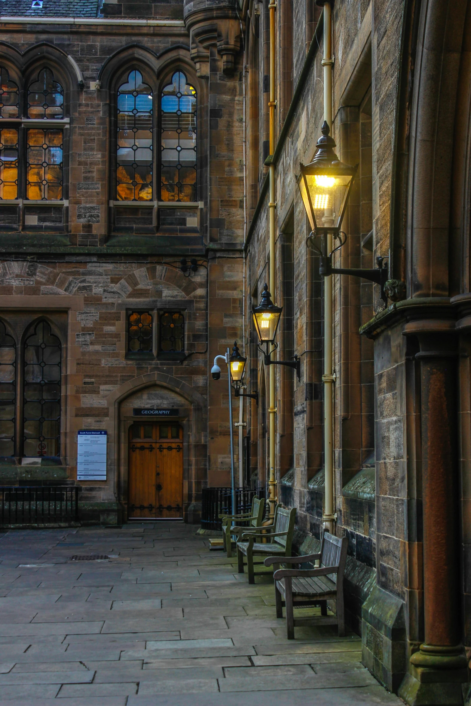 a couple of benches and lights are near an old building