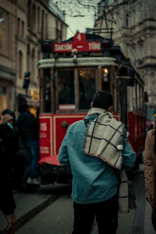 a person with a large backpack standing by a streetcar