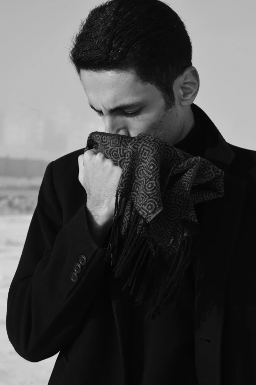 a man wearing a jacket and scarf is holding his nose