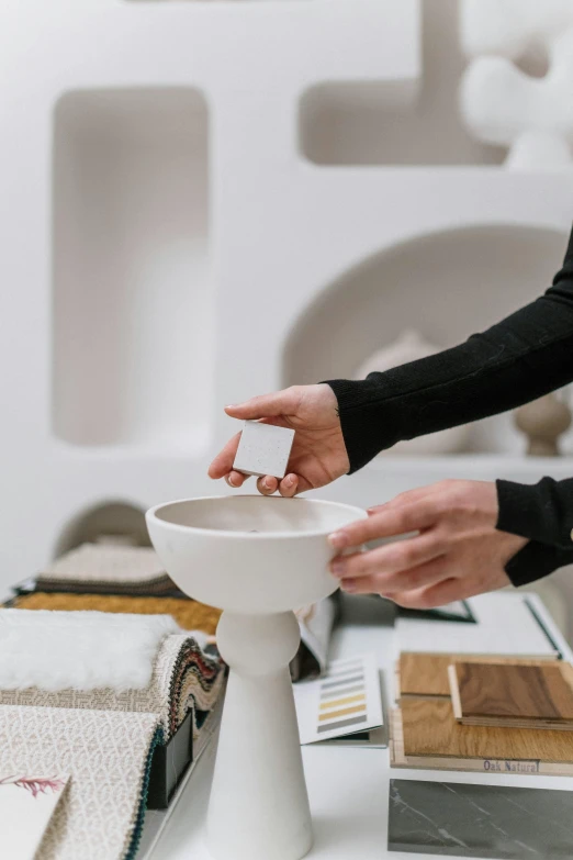 a person putting a business card in a white pedestal