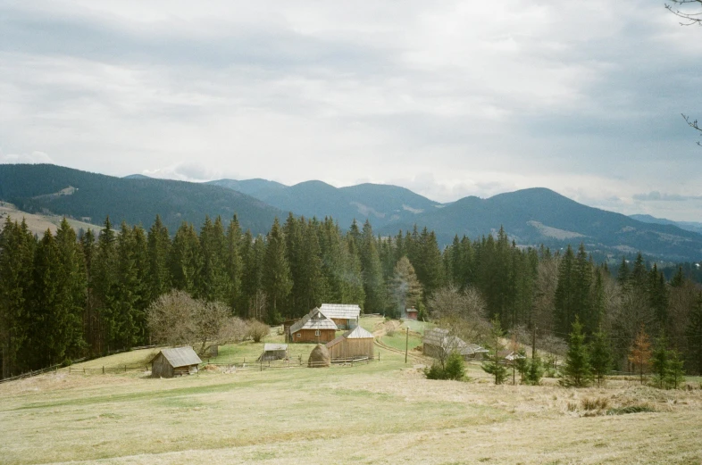 several cabins in the mountains, with trees and clouds