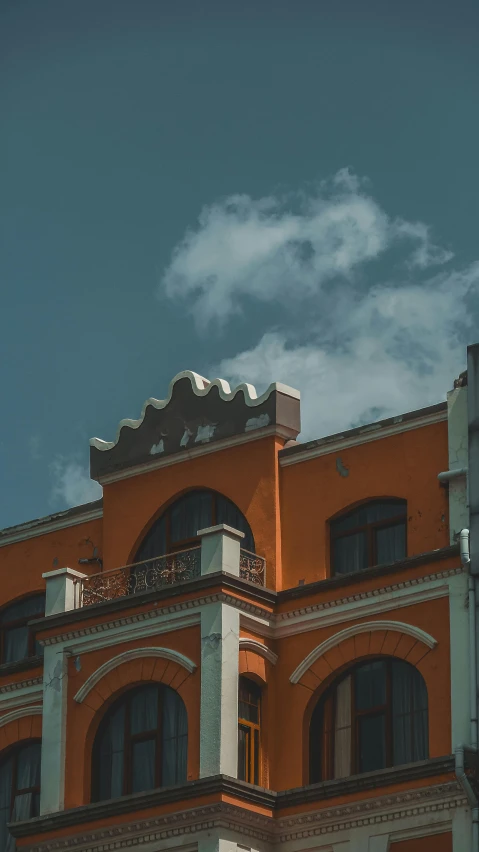 a view of an orange building with clouds in the background