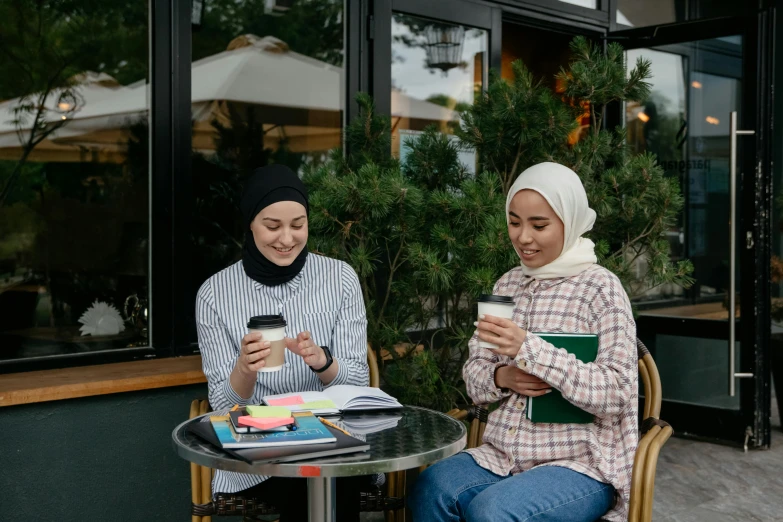 two people sit at a small table outside a cafe