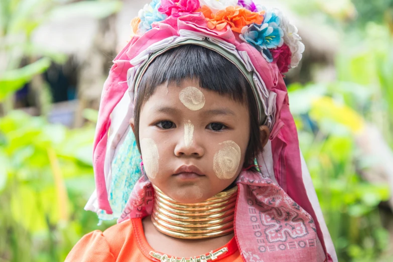 a little girl in orange and pink with gold markings on her face