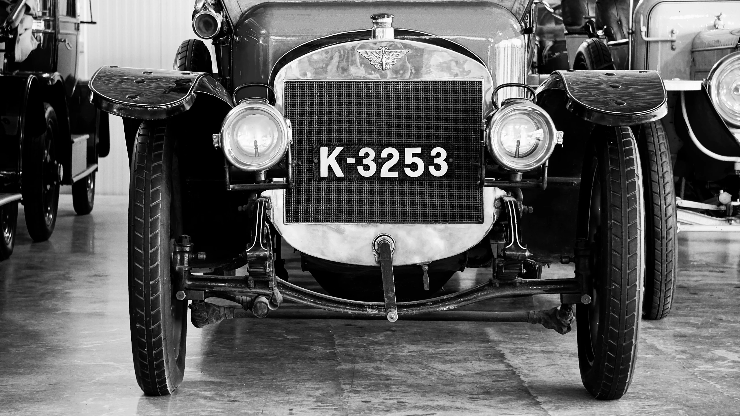an old black and white po of two vintage automobiles in a garage