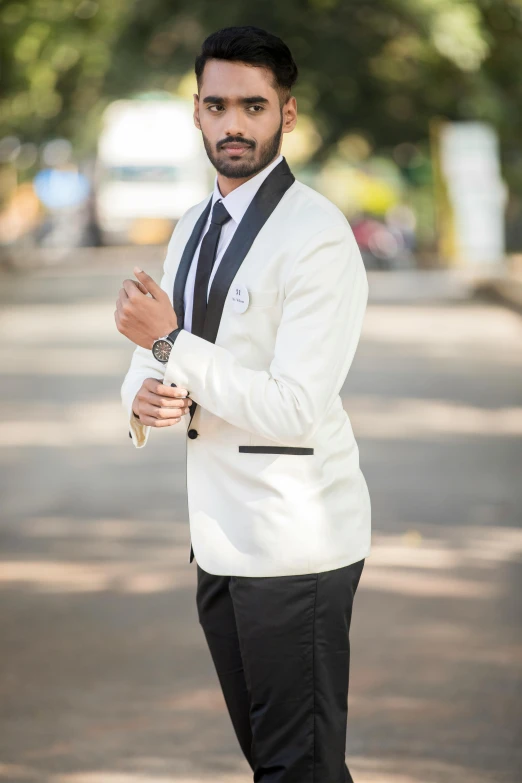 a man with his arm folded wearing a white jacket and black tie