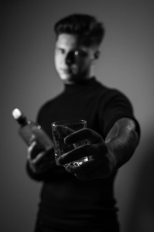 a man holding a drink looking at his cell phone