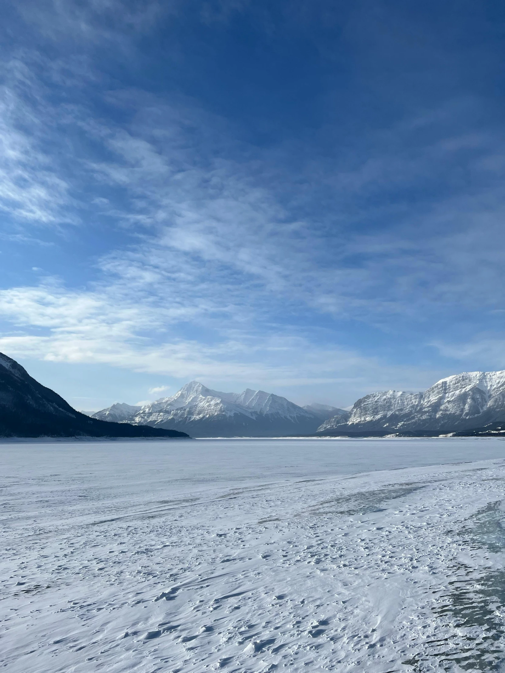 a snowy field and mountains under a cloudy blue sky