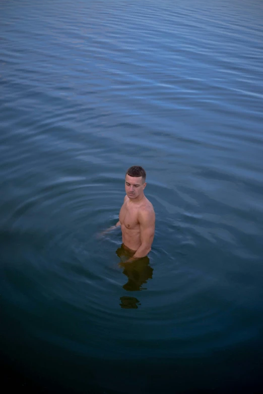 man swimming in dark body of water on clear day