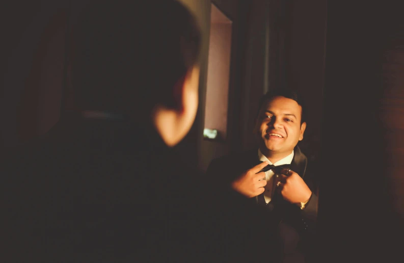 a man is helping a friend adjust his bowtie