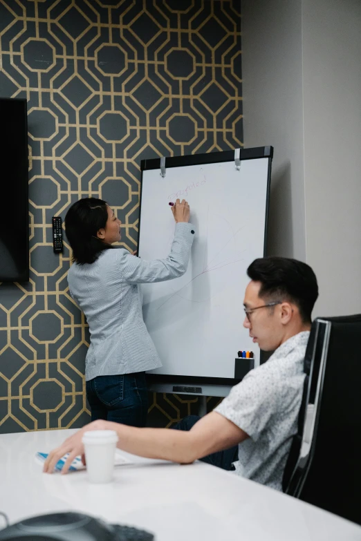 a man and woman in front of a white board