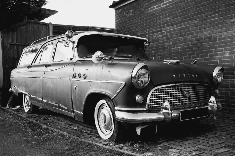 an old car sitting in front of a brick wall