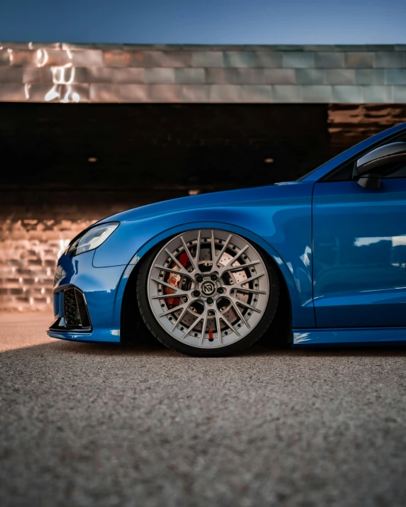 blue sports car parked on pavement next to brick building