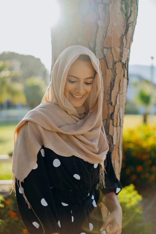 smiling woman with hijab leaning against tree